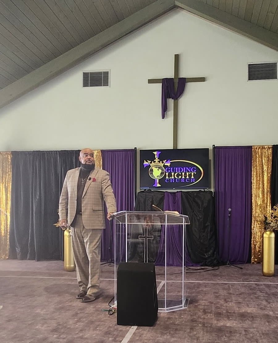 Pastor Eugene Moore standing beside the pulpit at Guiding Light Church